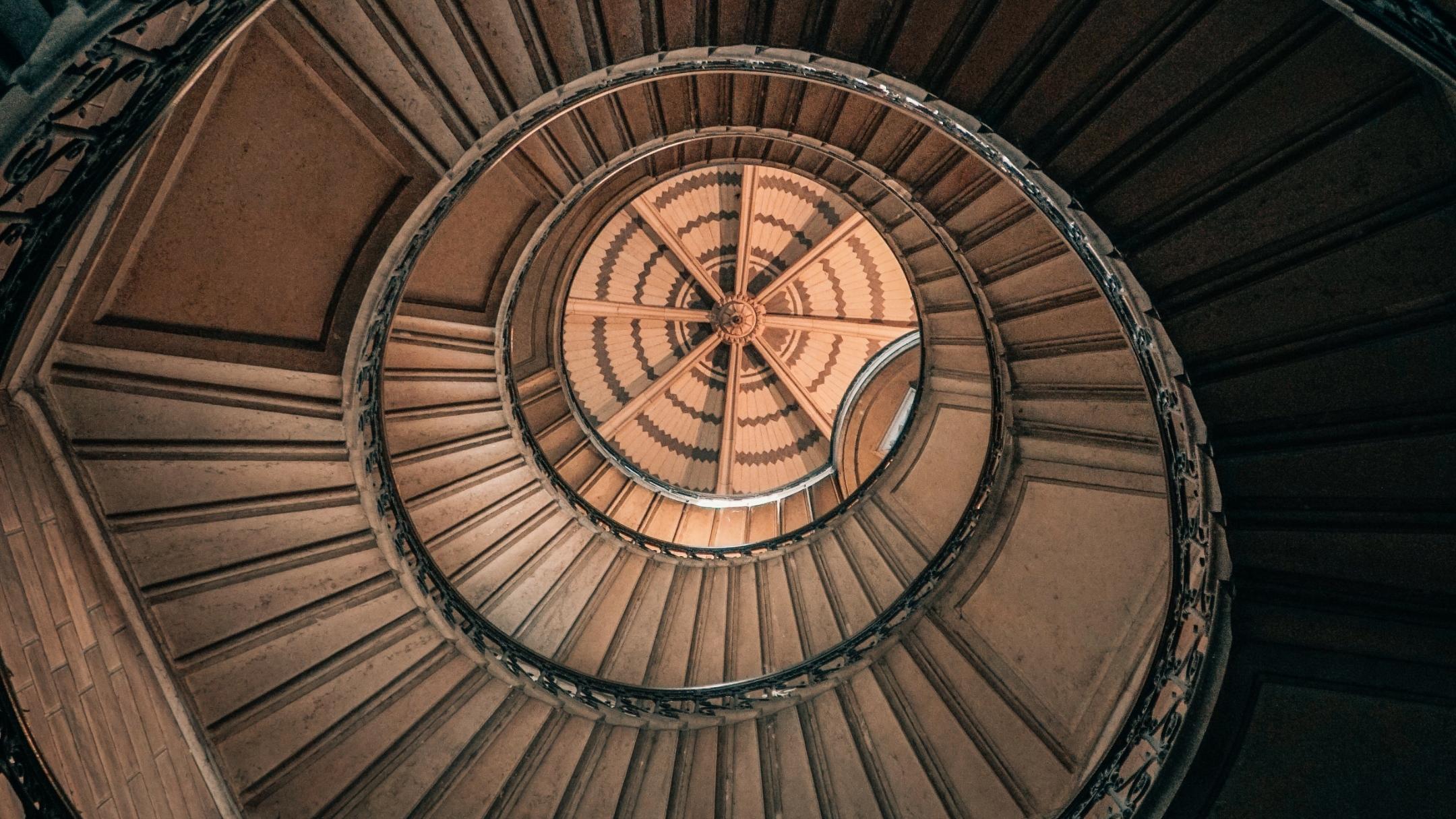 Blick von unten nach oben in ein rundes Treppenhaus.