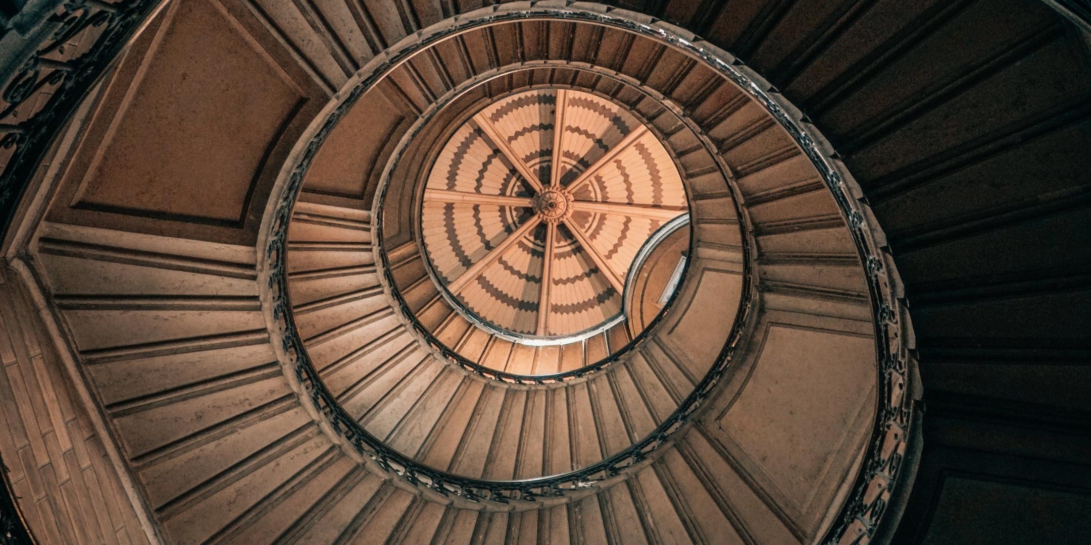 Blick von unten nach oben in ein rundes Treppenhaus.