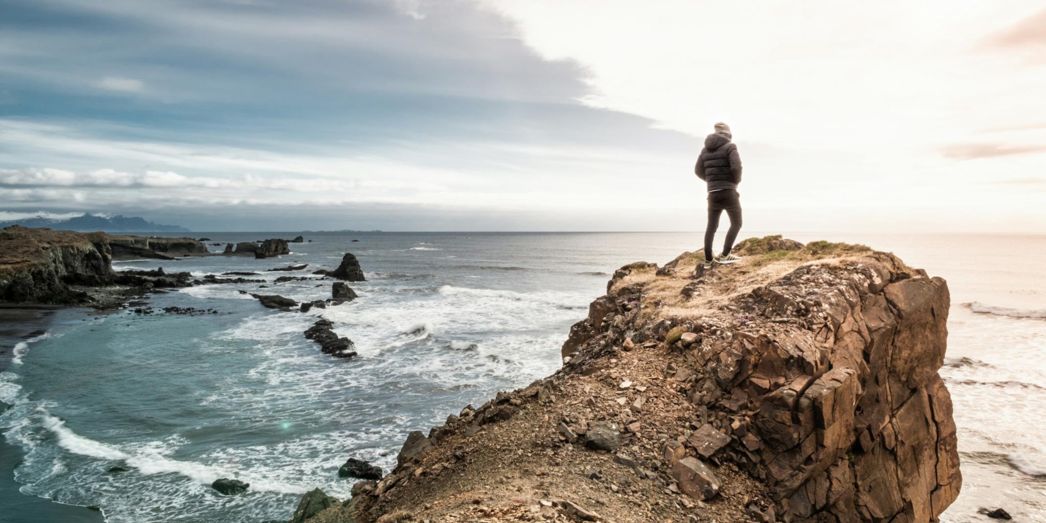 Eine Person steht auf einem Felsen am Meer