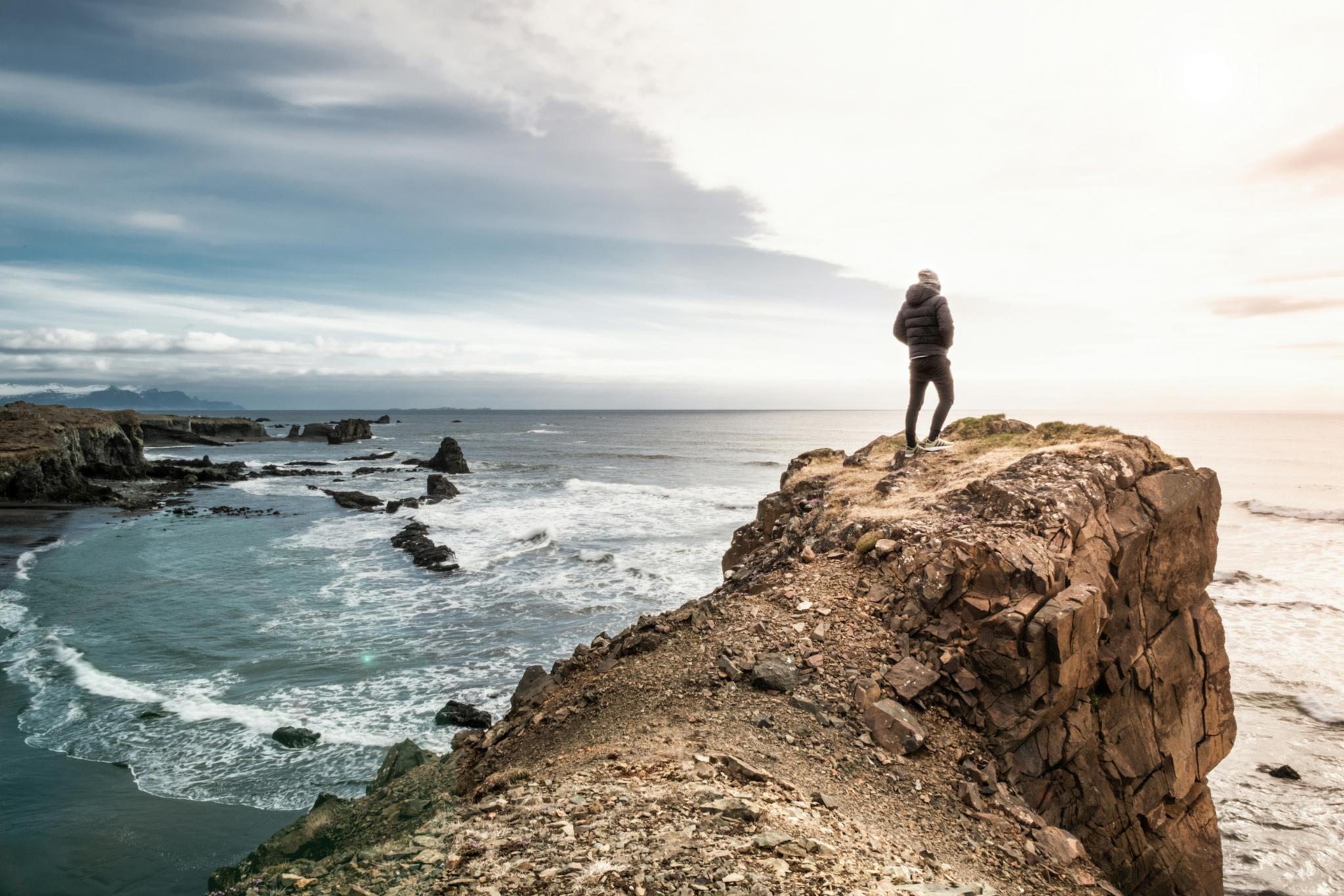 Eine Person steht auf einem Felsen am Meer