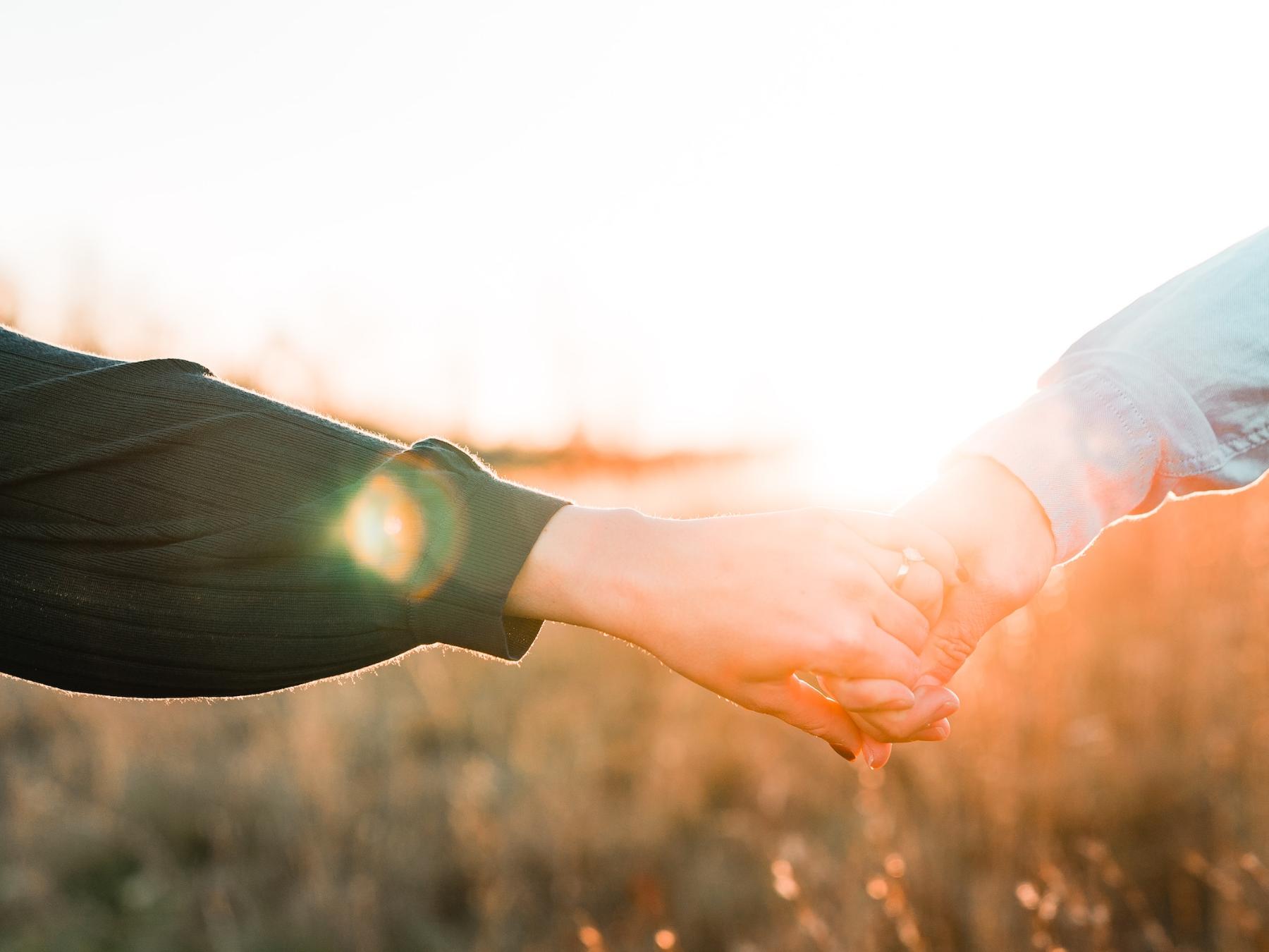 Zwei Menschen reichen sich die Hand, im Hintergrund geht die Sonne strahlend unter (c) Joe Yates auf unsplash.com Zwei Menschen reichen sich die Hand, im Hintergrund geht die Sonne strahlend unter