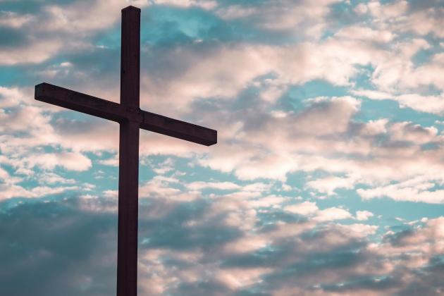 Ein Kreuz steht vor einem Himmel mit Wolken