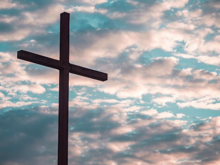 Ein Kreuz steht vor einem Himmel mit Wolken