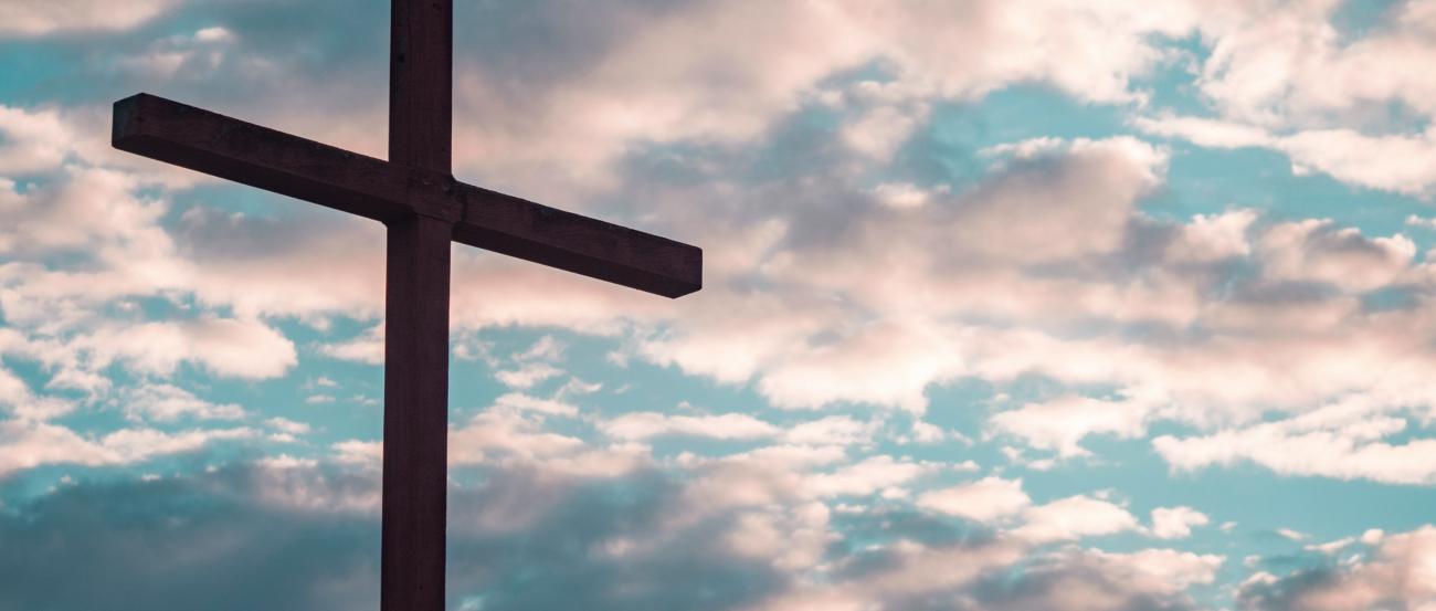 Ein Kreuz steht vor einem Himmel mit Wolken