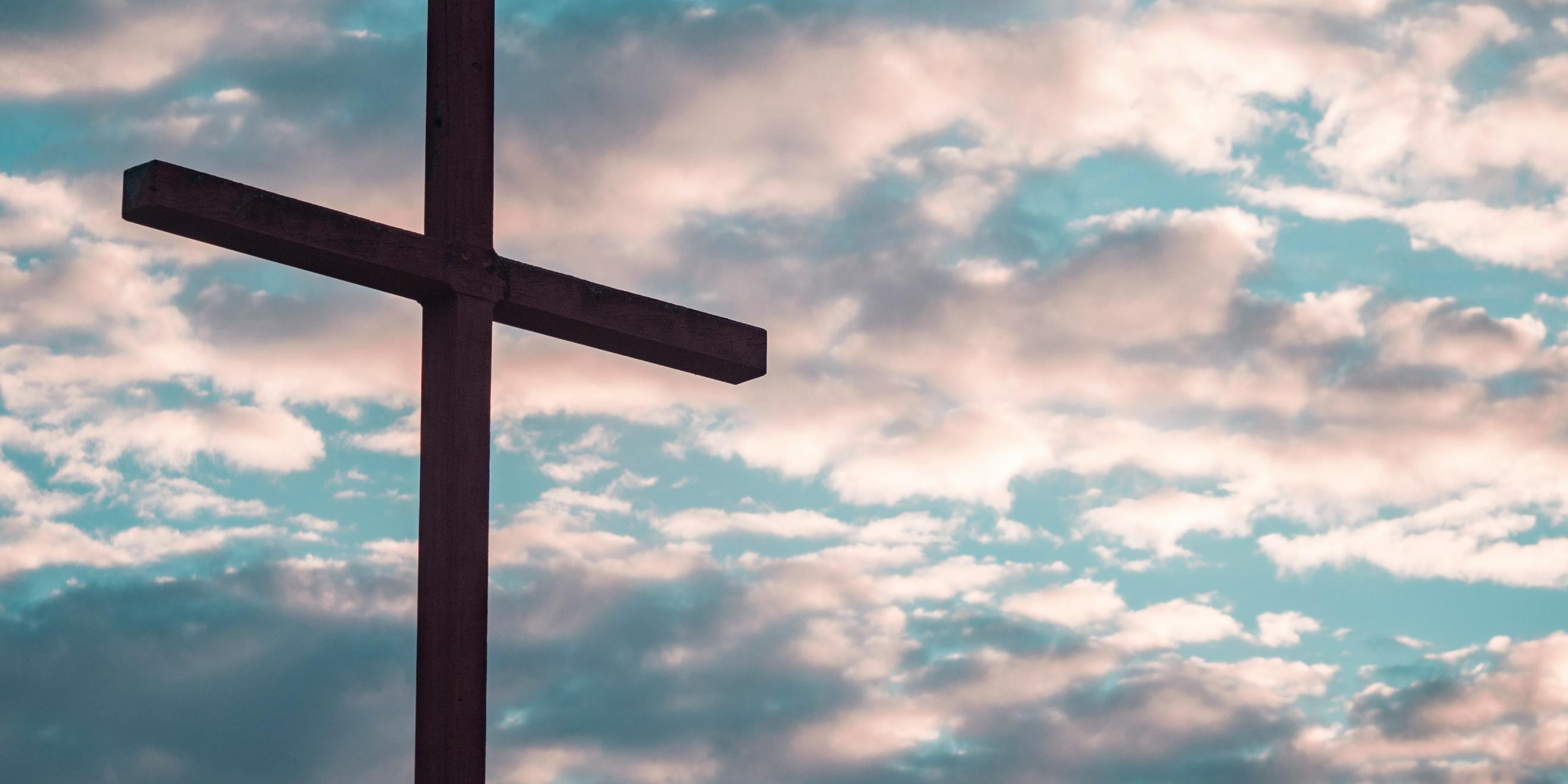 Ein Kreuz steht vor einem Himmel mit Wolken