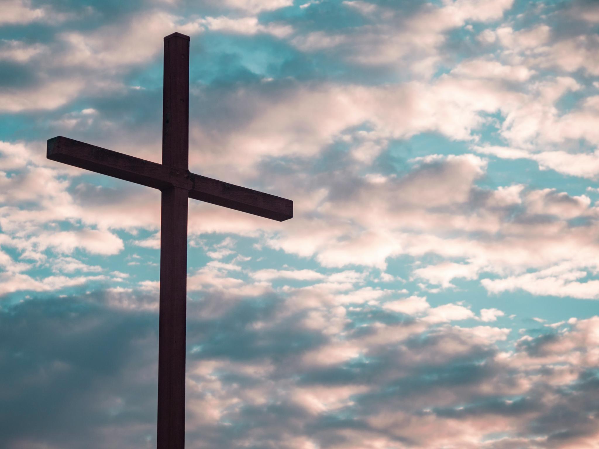 Ein Kreuz steht vor einem Himmel mit Wolken