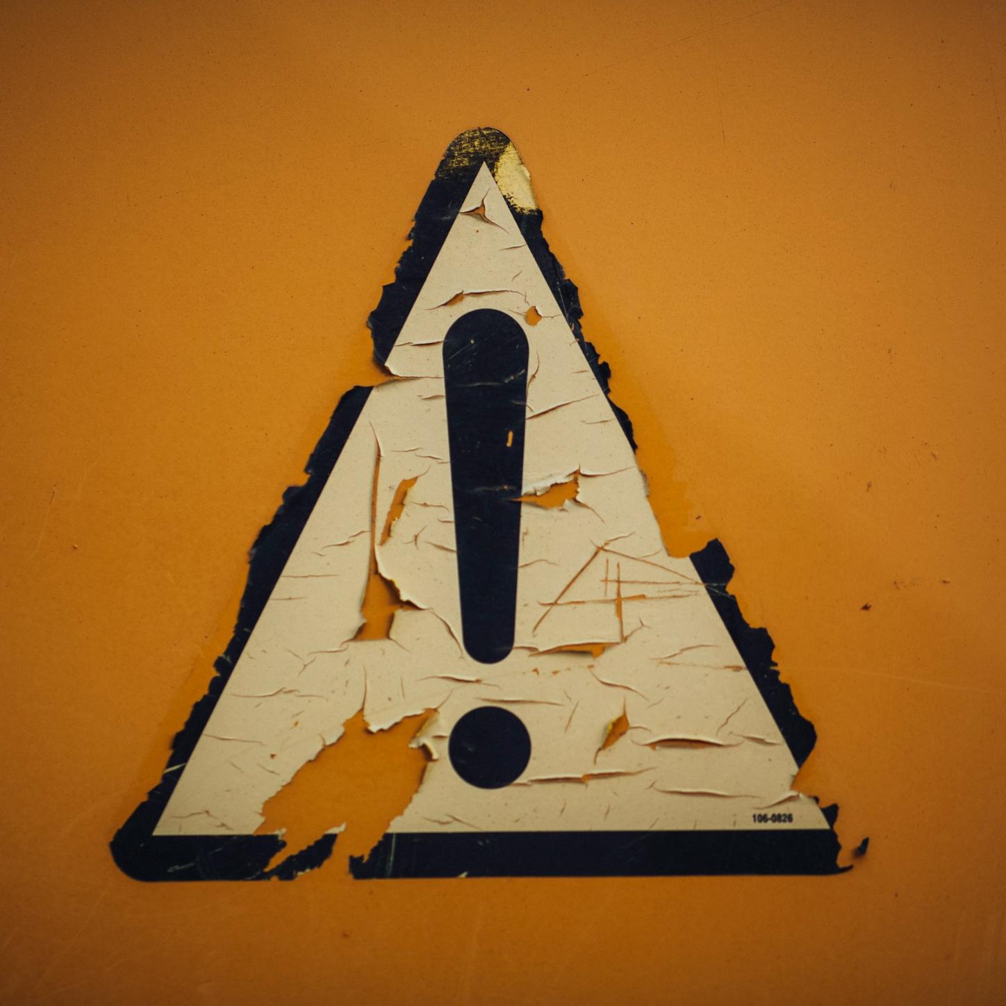 ein Schild mit Ausrufezeichen klebt an der Wand