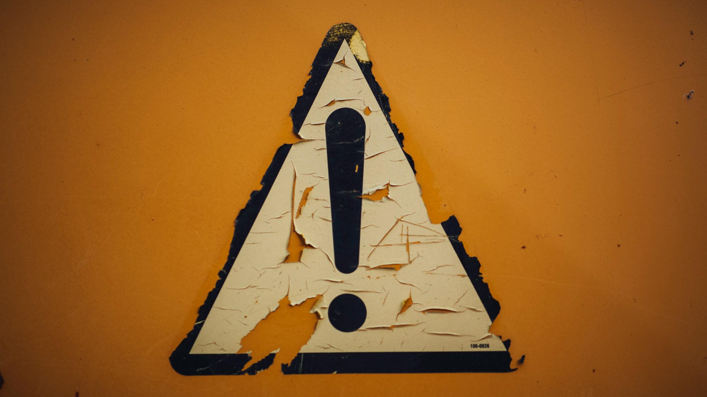 ein Schild mit Ausrufezeichen klebt an der Wand