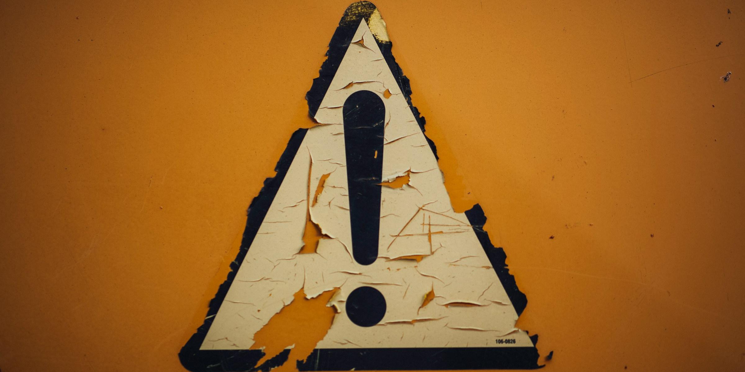 ein Schild mit Ausrufezeichen klebt an der Wand
