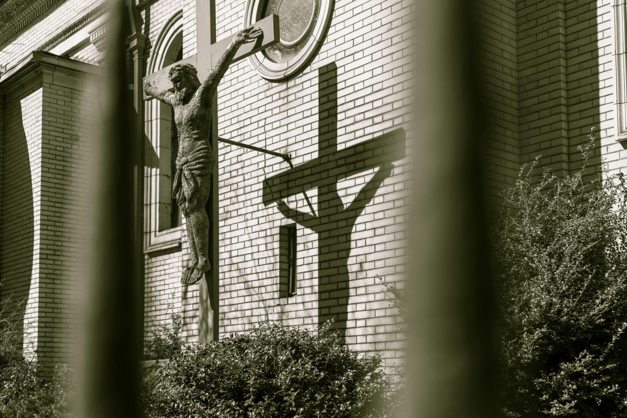Ein Kreuz steht vor einer Kirche mit Backsteinen