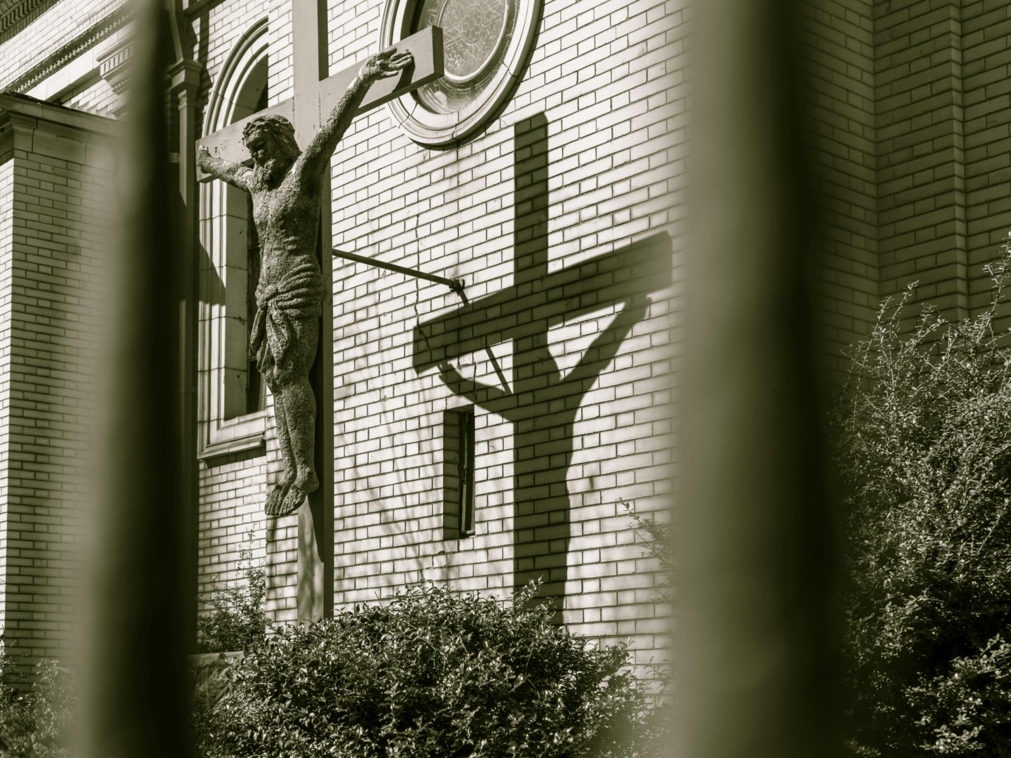 Ein Kreuz steht vor einer Kirche mit Backsteinen