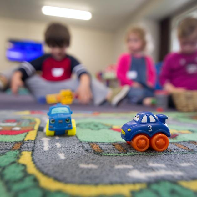 Auf einem Spielteppich stehen zwei kleine Spielzeugautos.