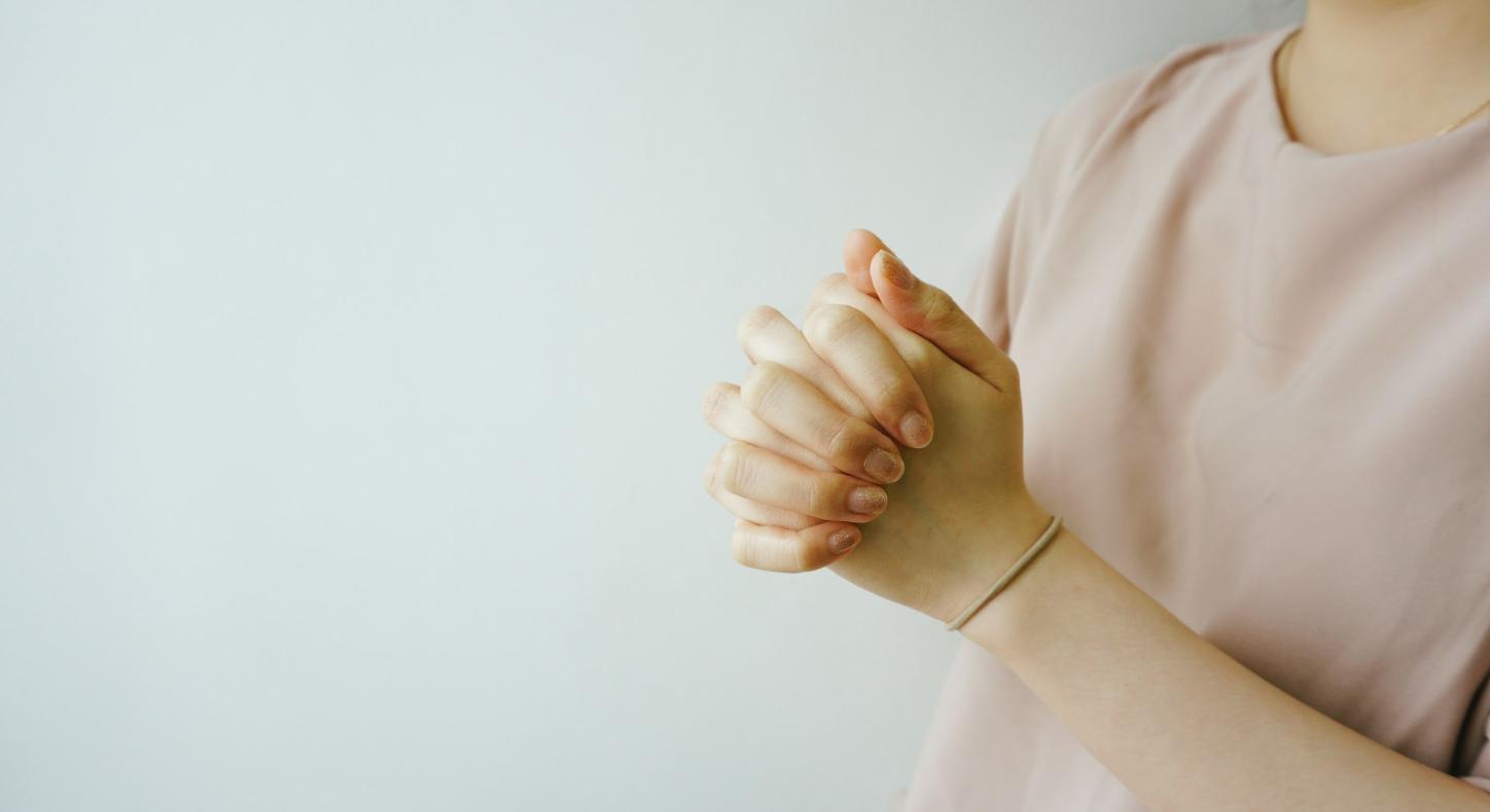 Eine Person faltet die Hände zum Gebet