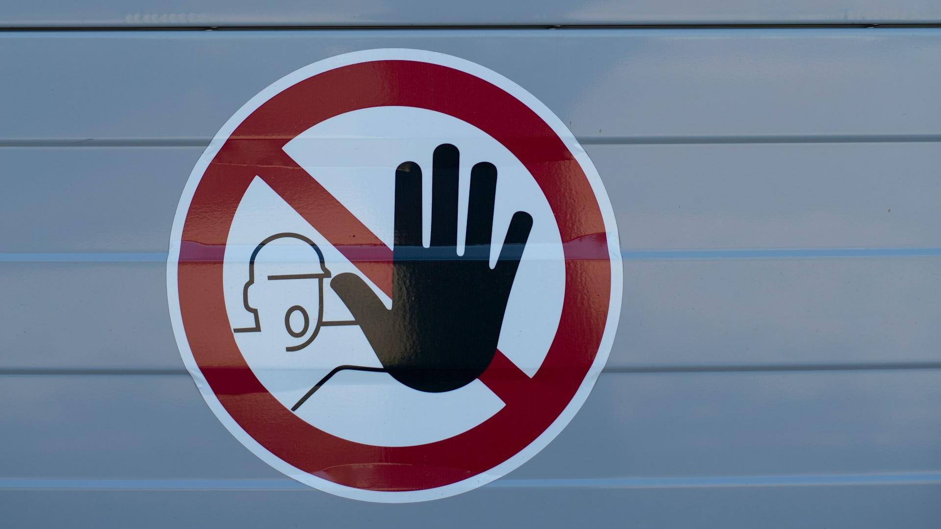 Symbol: Stopp-Hand vor Bauarbeiter im roten Kreis