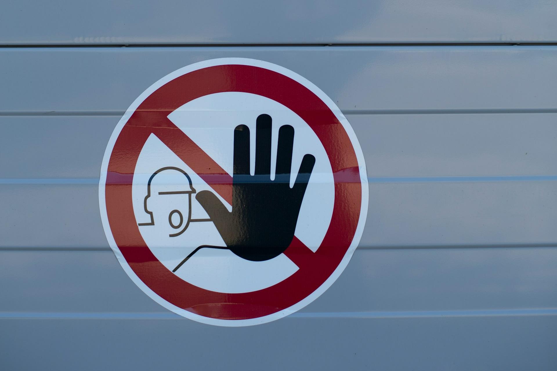 Symbol: Stopp-Hand vor Bauarbeiter im roten Kreis