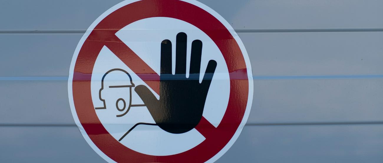 Symbol: Stopp-Hand vor Bauarbeiter im roten Kreis
