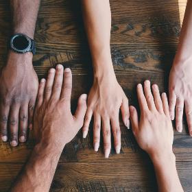 5 Hände in allen Farben verschiedener Nationen liegen auf einem  Tisch