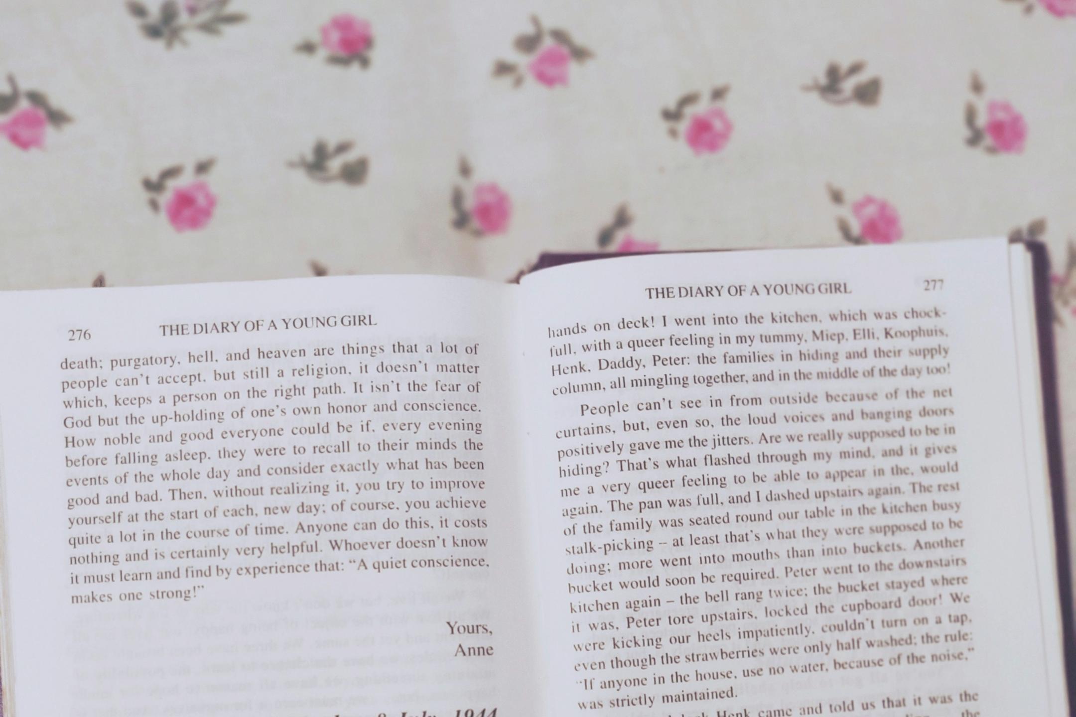 Auf einem Tisch mit Blumendecke liegt das geöffnete Tagebuch der Anne Frank in englischer Sprache
