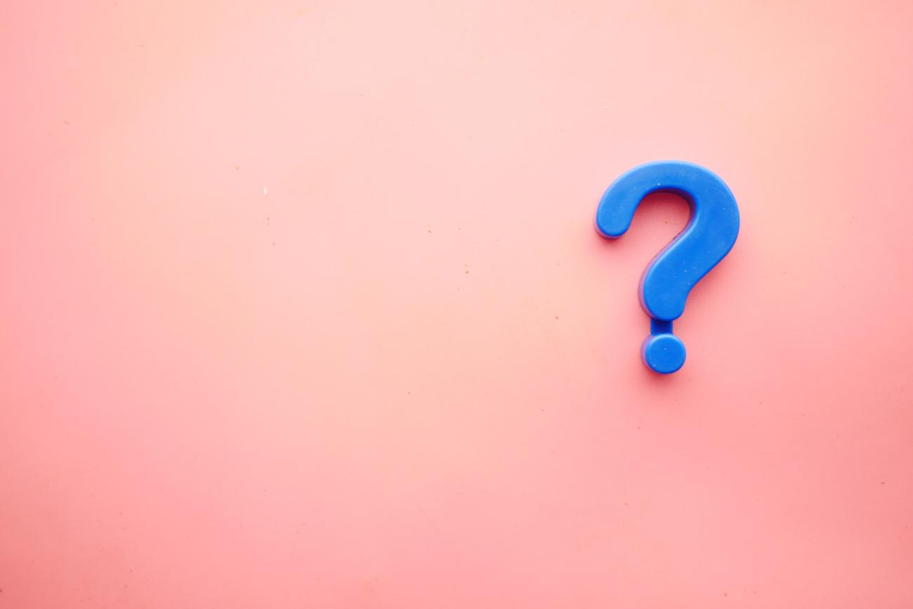 Fragen? (c) Towfiqu barbhuiya auf Unsplash Man sieht ein blaues Fragezeichen auf einem rosafarbenen Hintergrund liegen