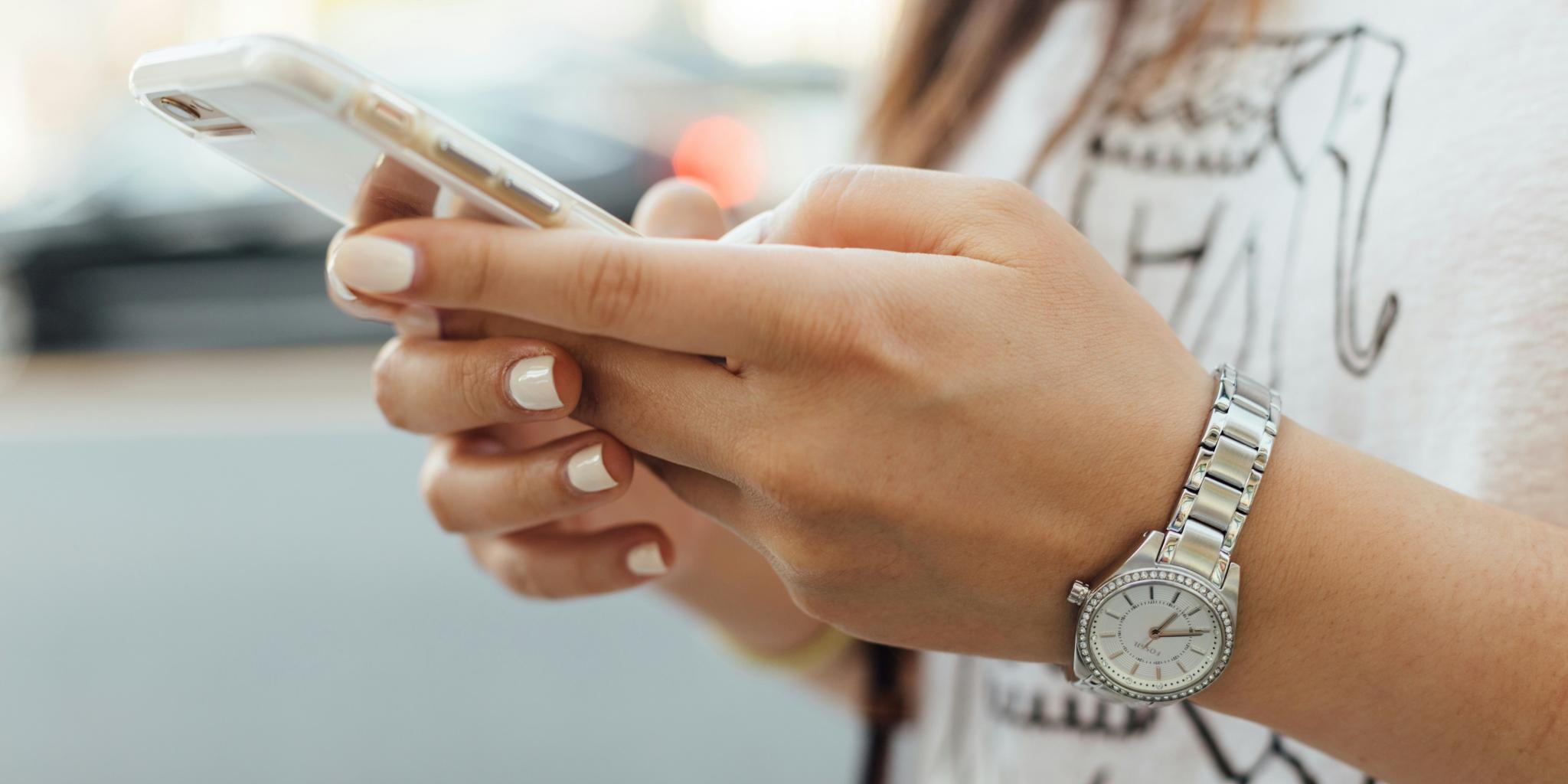 Zwei Hände mit lackierten Nägeln halten ein Handy.