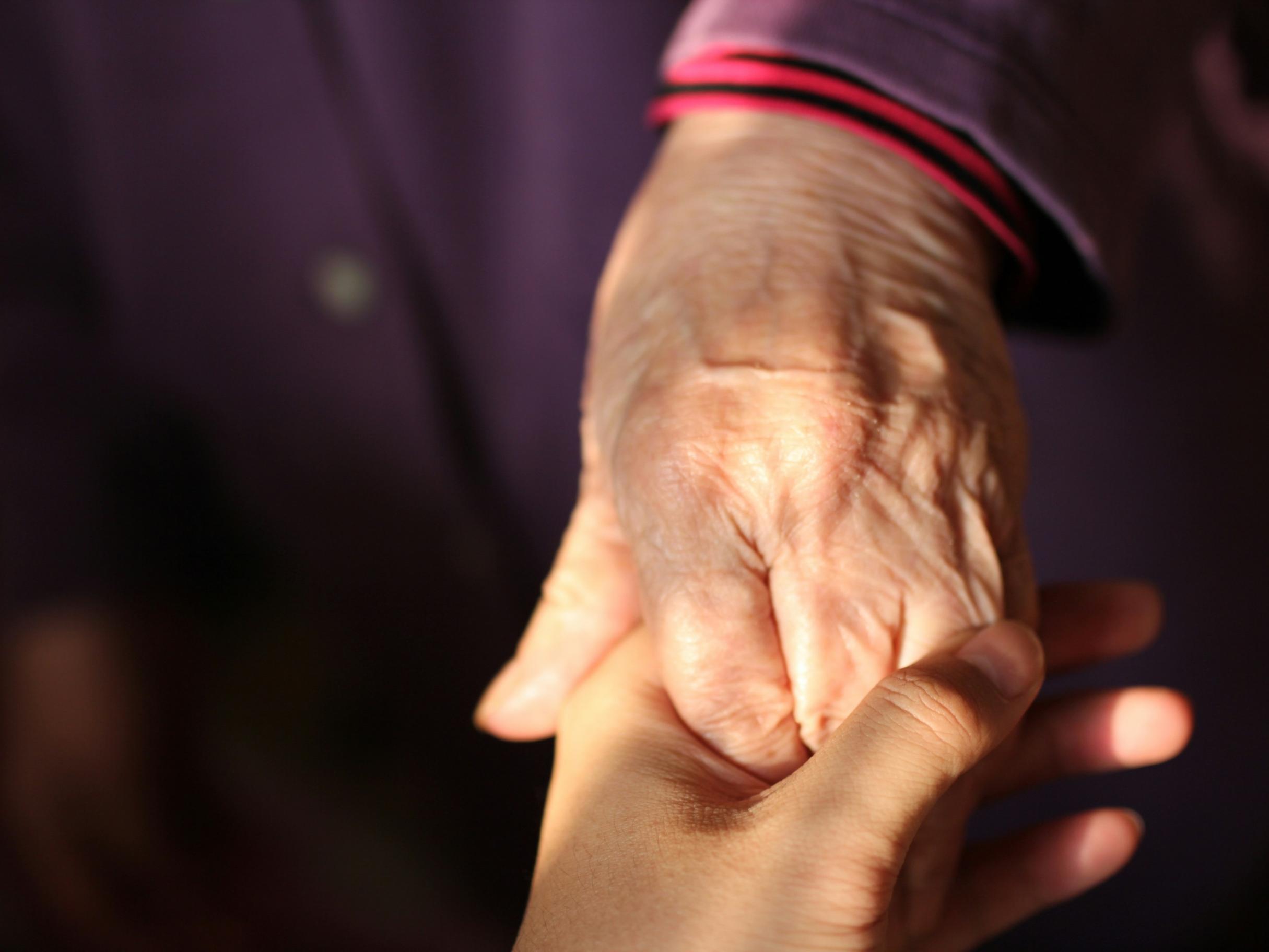 Eine ältere Hand hält eine jüngere Hand.