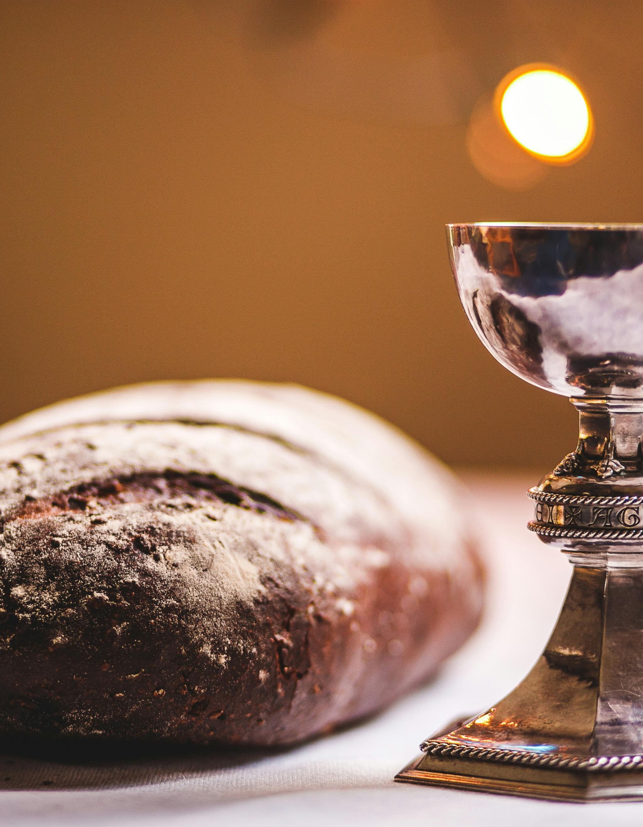 Auf einem Tisch liegt ein Laib Brot und ein silber glänzender Kelch