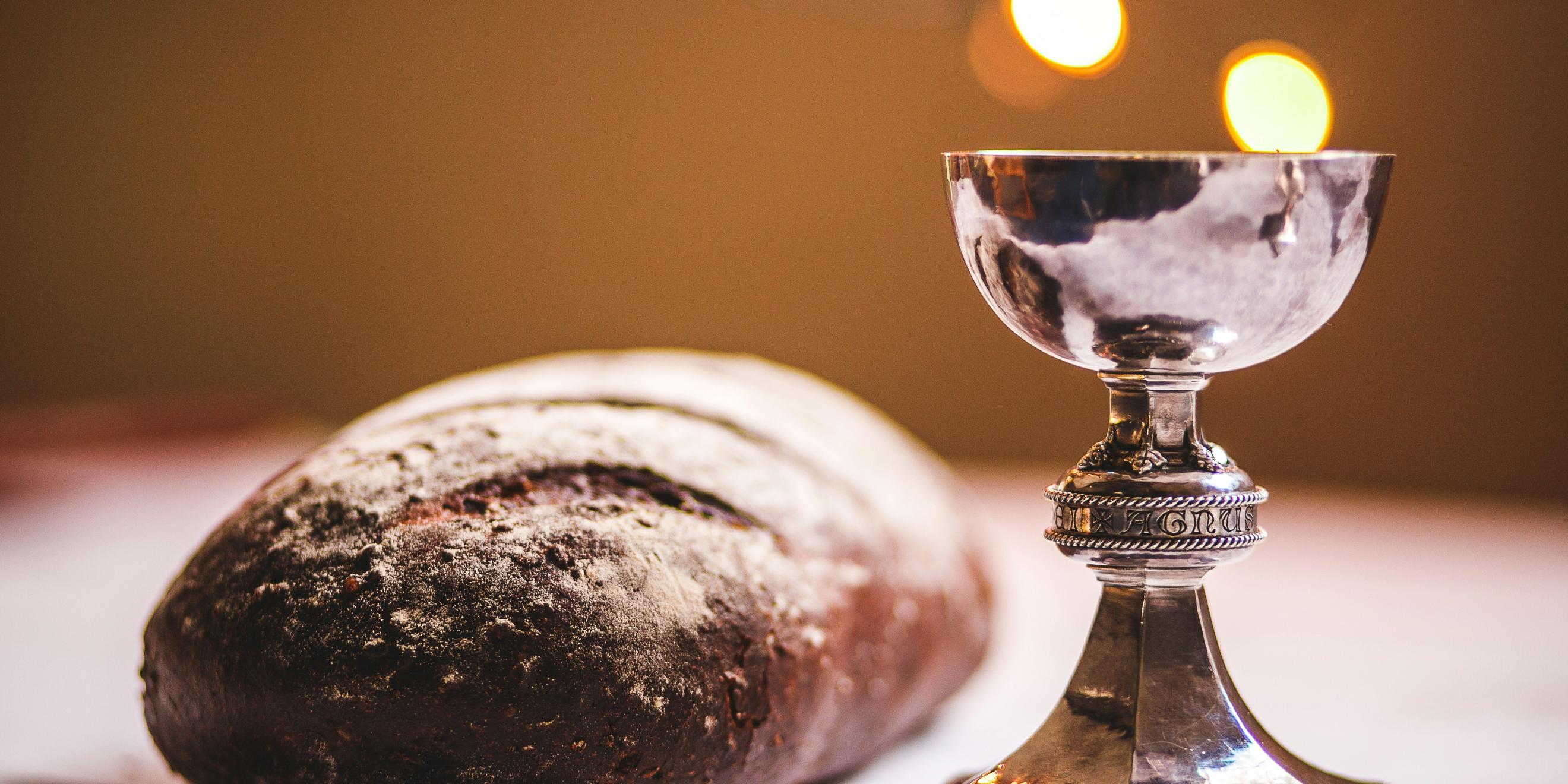 Auf einem Tisch liegt ein Laib Brot und ein silber glänzender Kelch