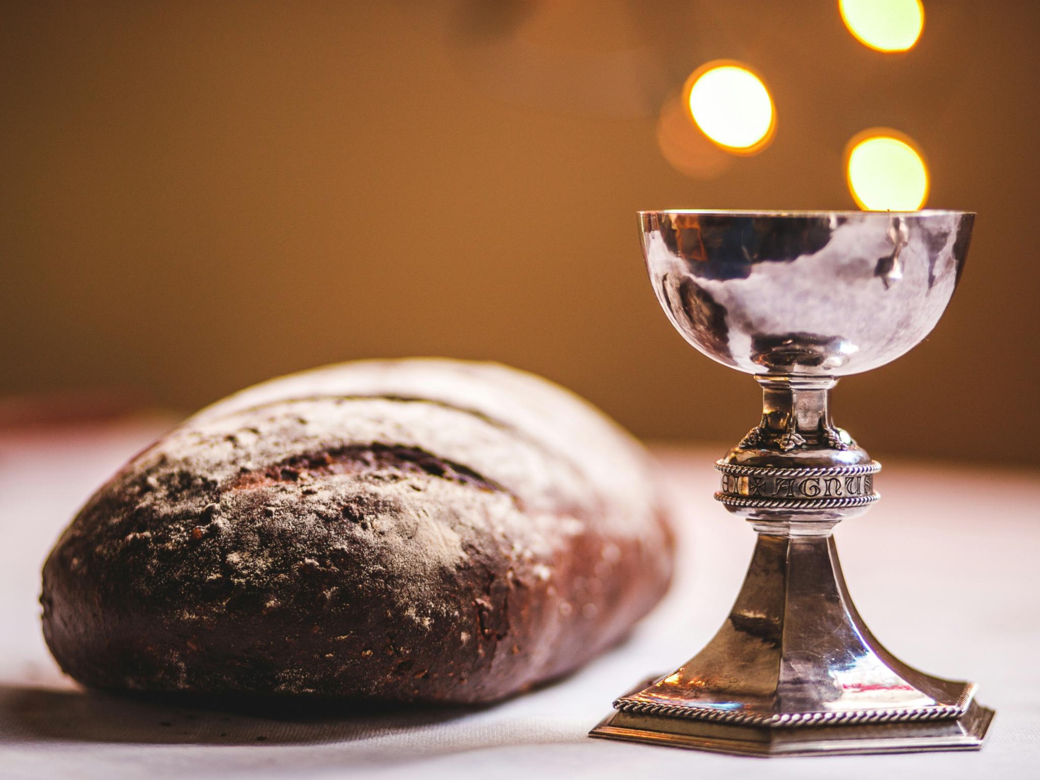 Auf einem Tisch liegt ein Laib Brot und ein silber glänzender Kelch