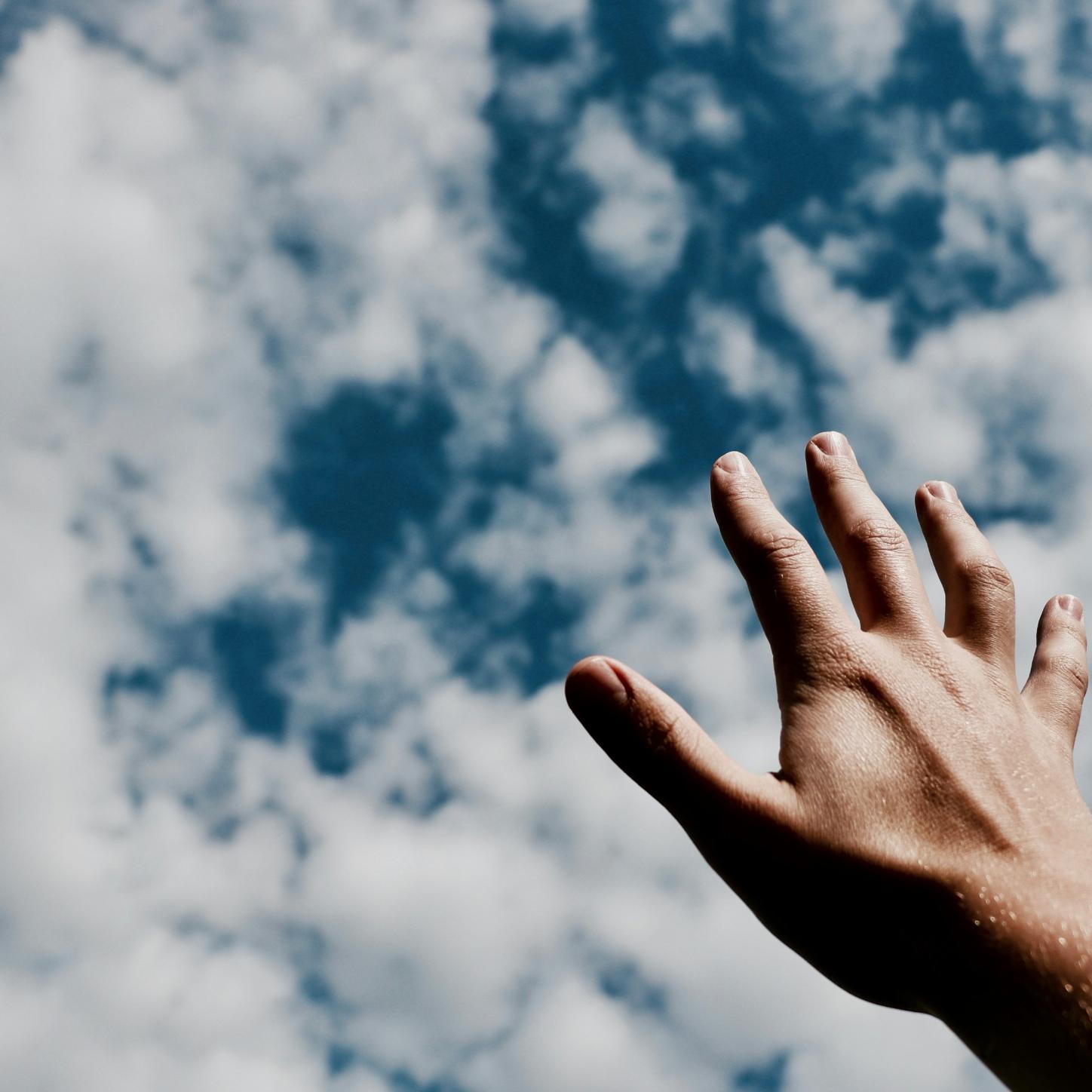 Eine Hand wird Richtung Himmel ausgestreckt