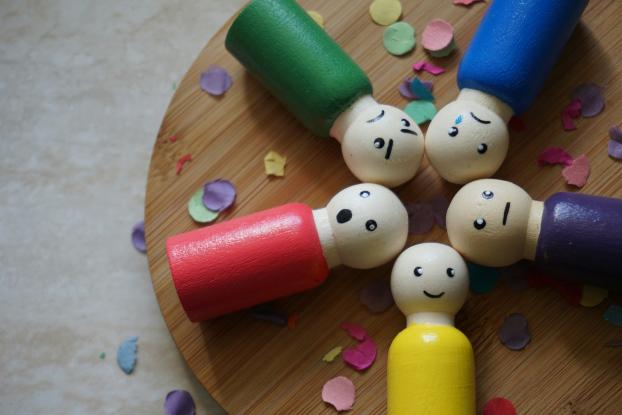 Bunte Figuren aus Holz mit verschiedenen Gesichtsausdrücken liegen auf einem runden Holztablett (c) Joanne Glaudemans / unsplash.com Bunte Figuren aus Holz mit verschiedenen Gesichtsausdrücken liegen auf einem runden Holztablett