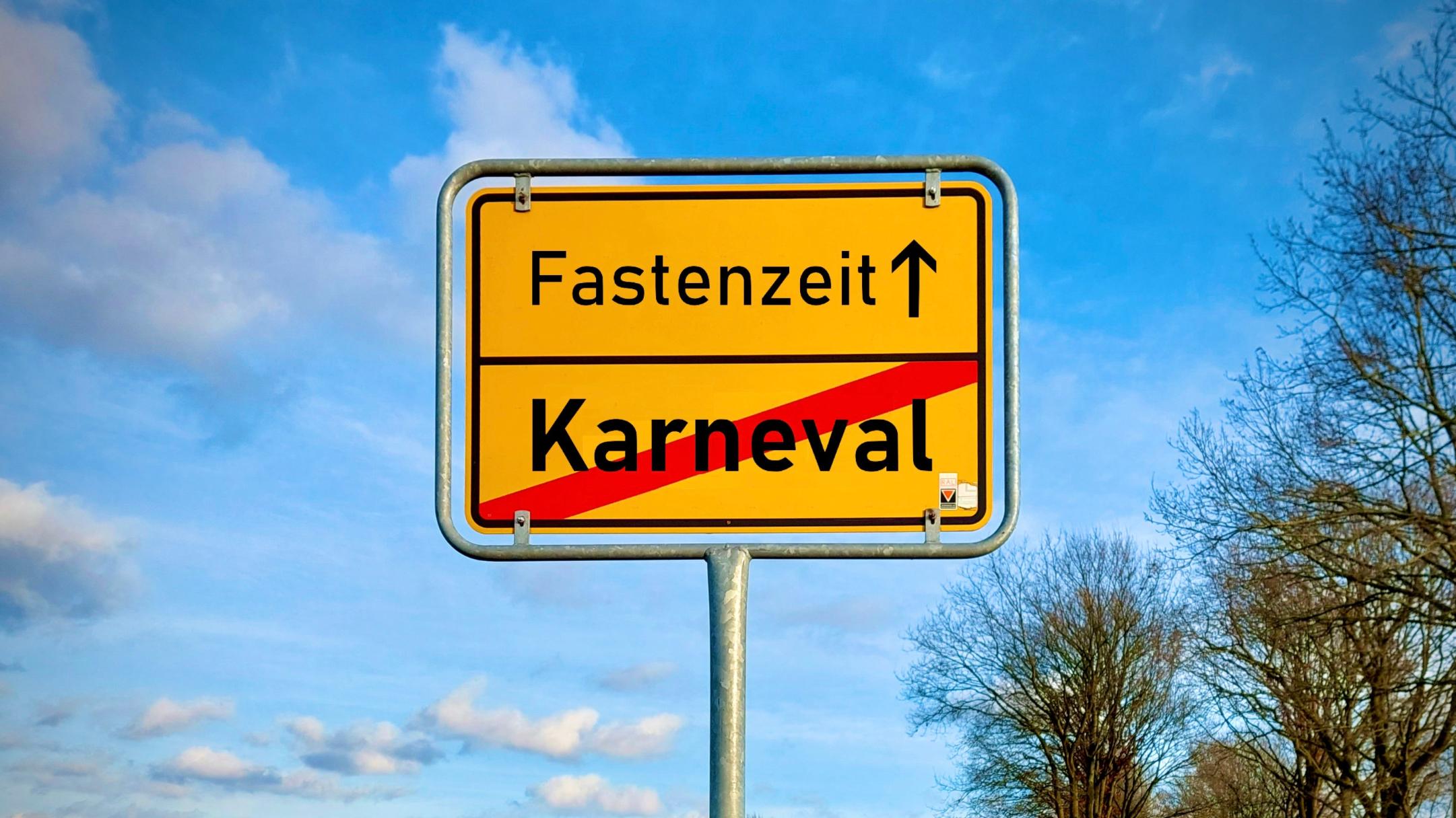 Ein Ortschild in Geld auf dem das Wort Karneval durchgestrichen ist. Darüber steht Fastenzeit mit einem Pfeil der nach vorne weist