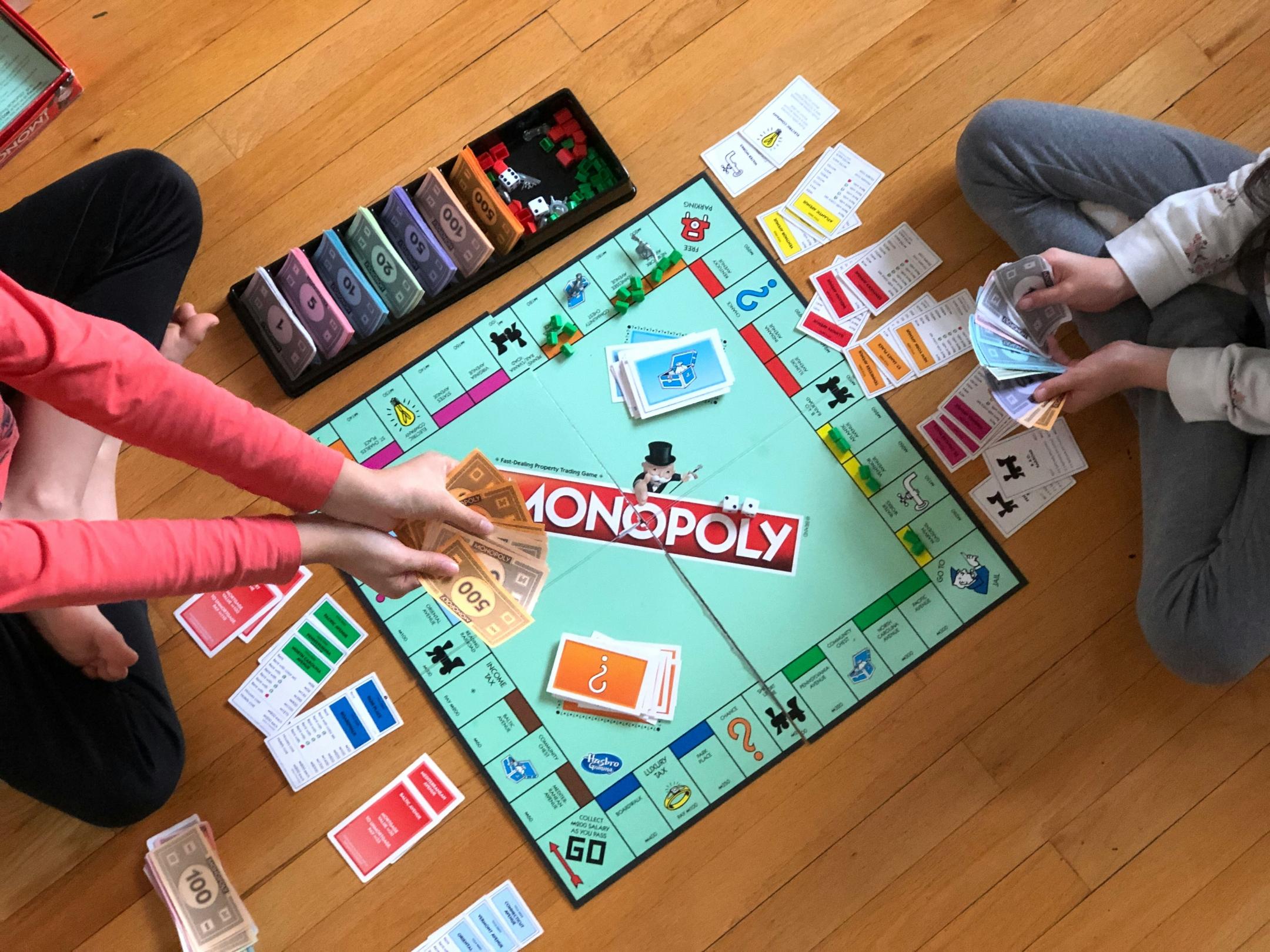 Blick von oben: zwei Kinder spielen Monopoly