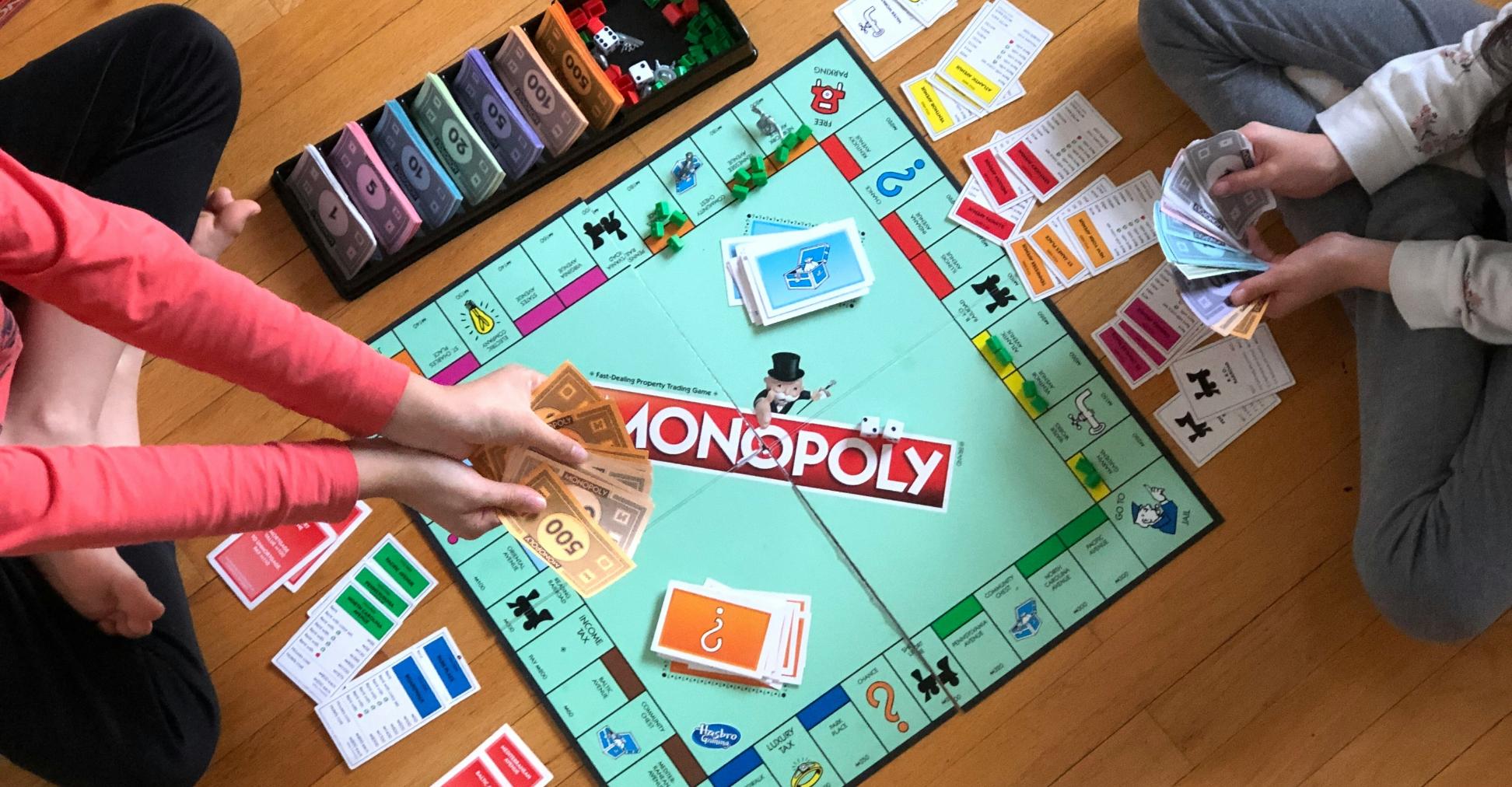 Blick von oben: zwei Kinder spielen Monopoly