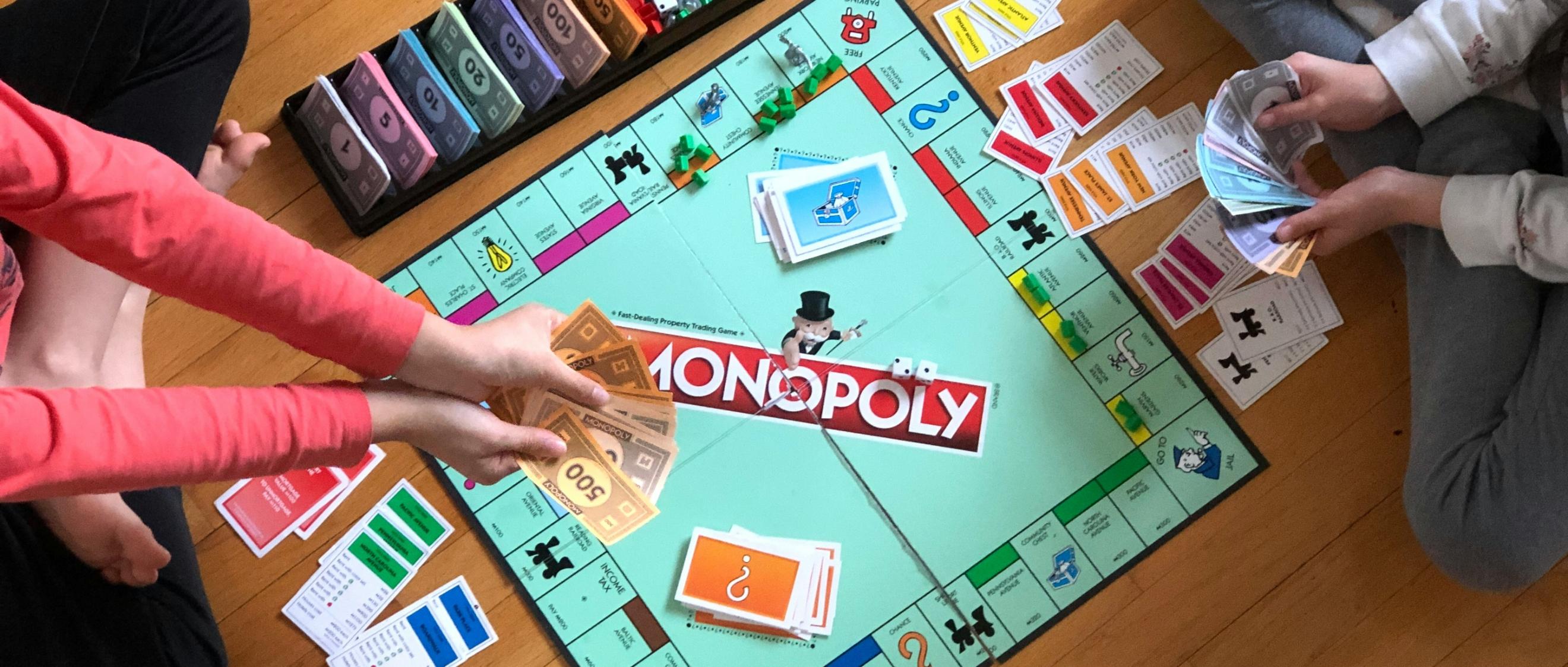 Blick von oben: zwei Kinder spielen Monopoly