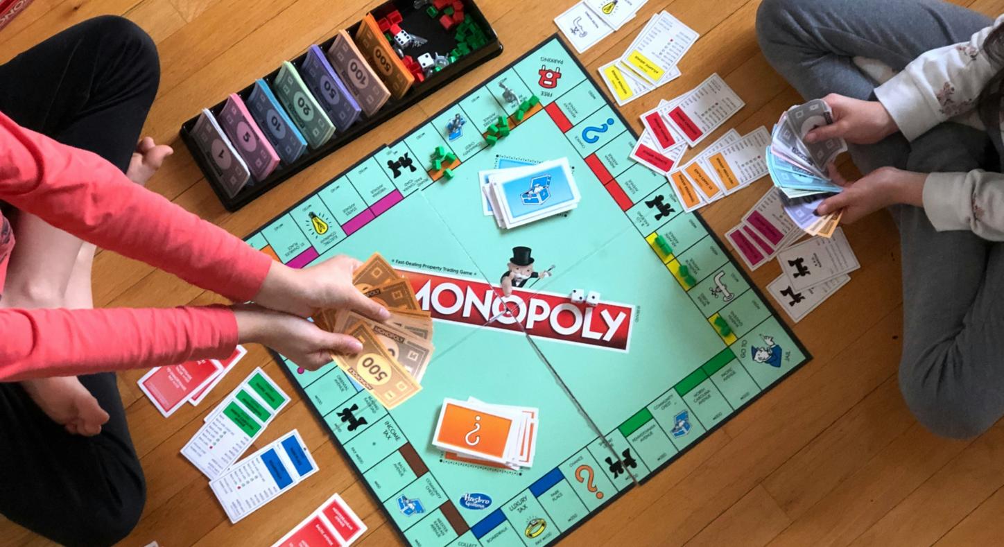 Blick von oben: zwei Kinder spielen Monopoly