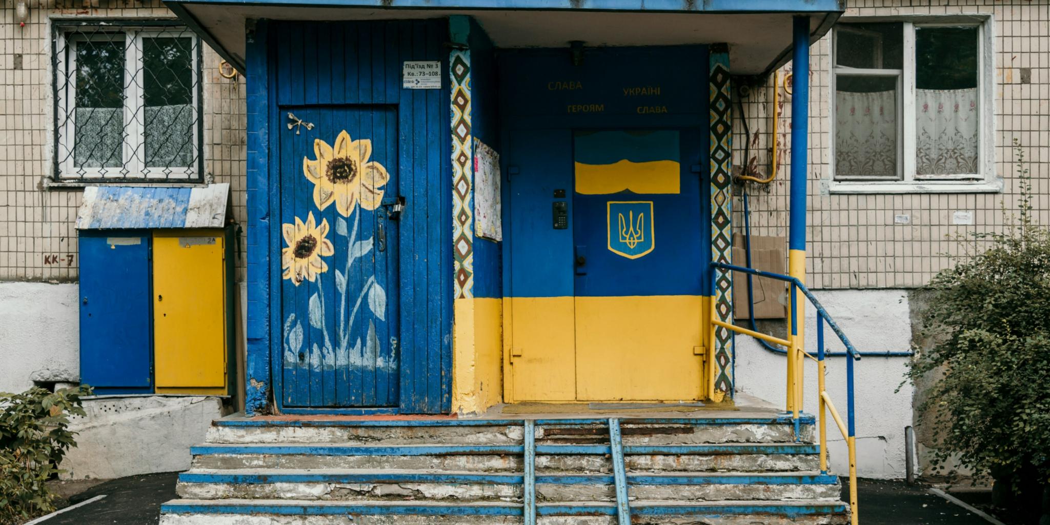 Eine Eingangstür zu einem tristen Haus ist in den Landesfarben der Ukraine gelb und blau bemalt