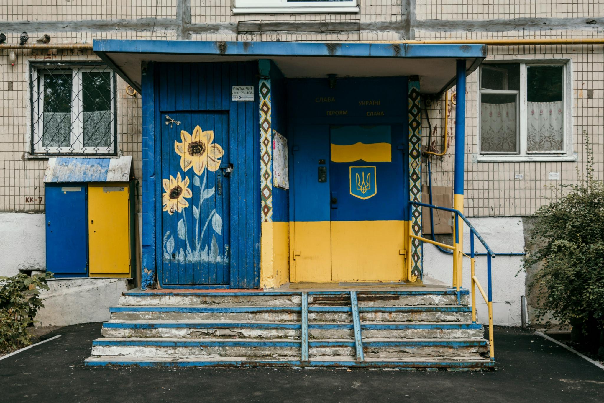 Eine Eingangstür zu einem tristen Haus ist in den Landesfarben der Ukraine gelb und blau bemalt