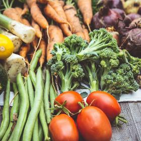 Zucchini, Lauch, Karotten, Zwiebeln, Bohnen, Tomaten und Broccoli liegen auf einem Tisch aus Holz