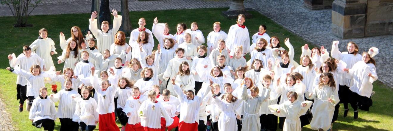 Blick auf eine Messdienergruppe im Freien von oben. Die Kinder und Jugendlichen springen in die Luft
