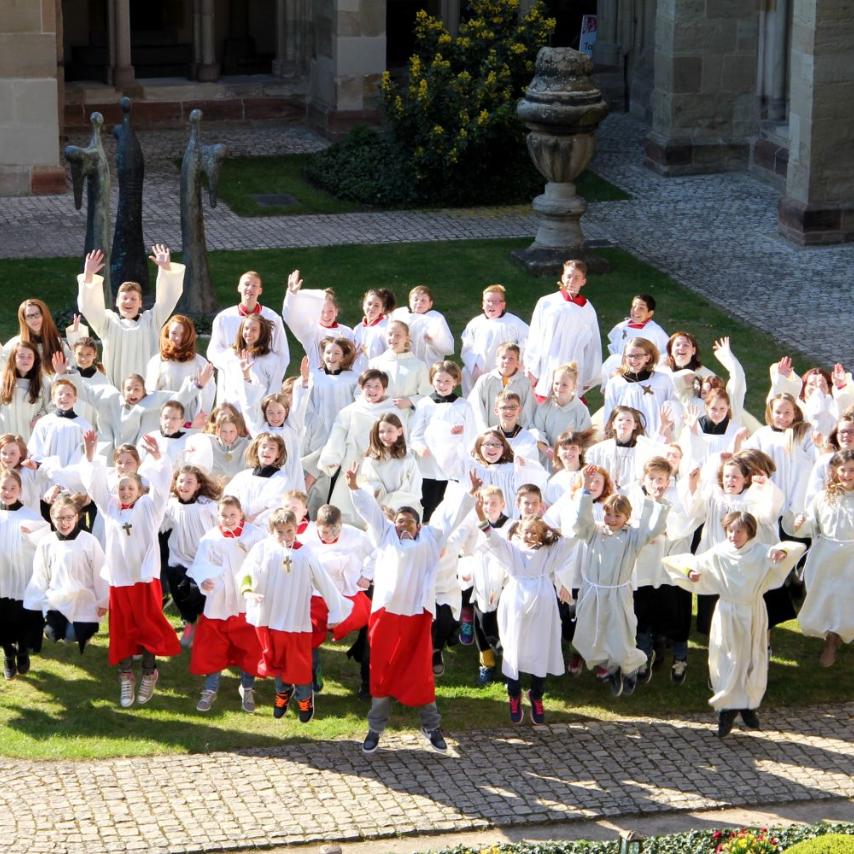 Blick auf eine Messdienergruppe im Freien von oben. Die Kinder und Jugendlichen springen in die Luft