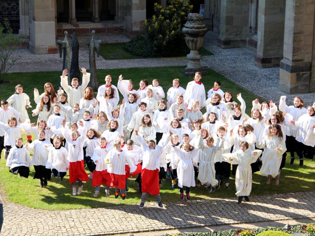 Blick auf eine Messdienergruppe im Freien von oben. Die Kinder und Jugendlichen springen in die Luft