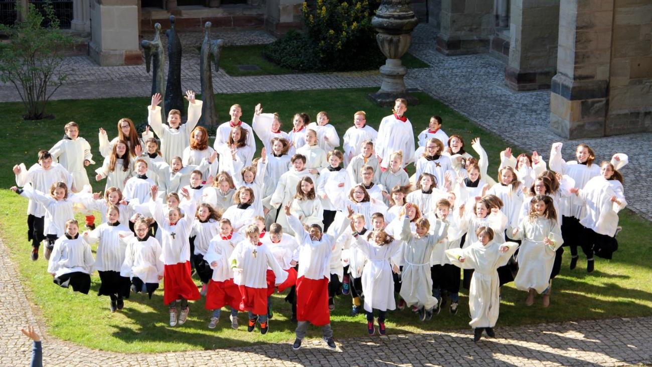 Blick auf eine Messdienergruppe im Freien von oben. Die Kinder und Jugendlichen springen in die Luft