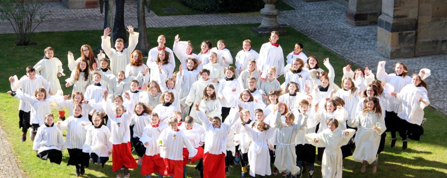 Blick auf eine Messdienergruppe im Freien von oben. Die Kinder und Jugendlichen springen in die Luft