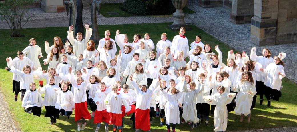Blick auf eine Messdienergruppe im Freien von oben. Die Kinder und Jugendlichen springen in die Luft