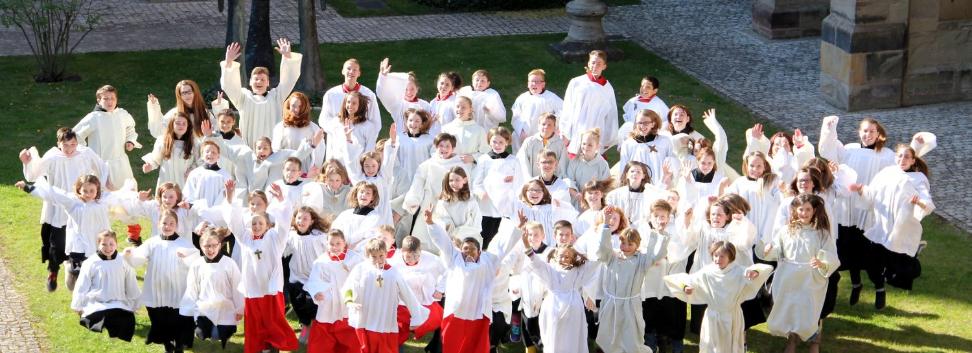 Blick auf eine Messdienergruppe im Freien von oben. Die Kinder und Jugendlichen springen in die Luft