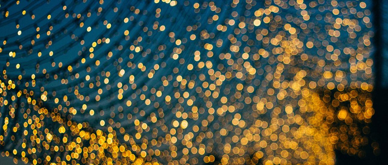 Licht (c) N Kamalov auf Unsplash Man sieht viele kleine unscharfe Lichtpunkte vor einem blauen Himmel