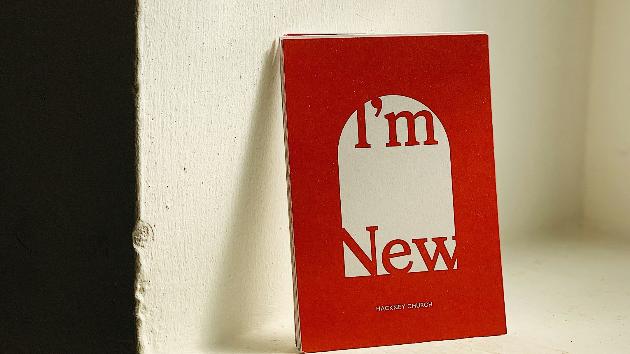 Ein rotes Buch lehnt an einem Fenstersims an der Wand. Auf dem Cover steht 'I'm new'