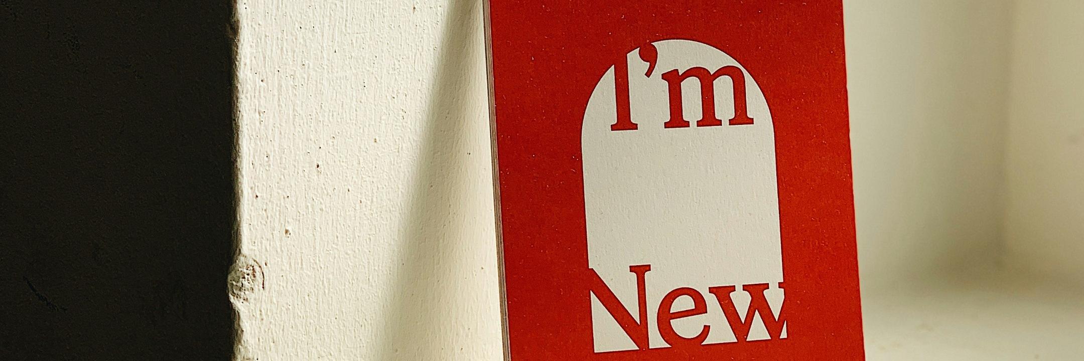 Ein rotes Buch lehnt an einem Fenstersims an der Wand. Auf dem Cover steht 'I'm new'