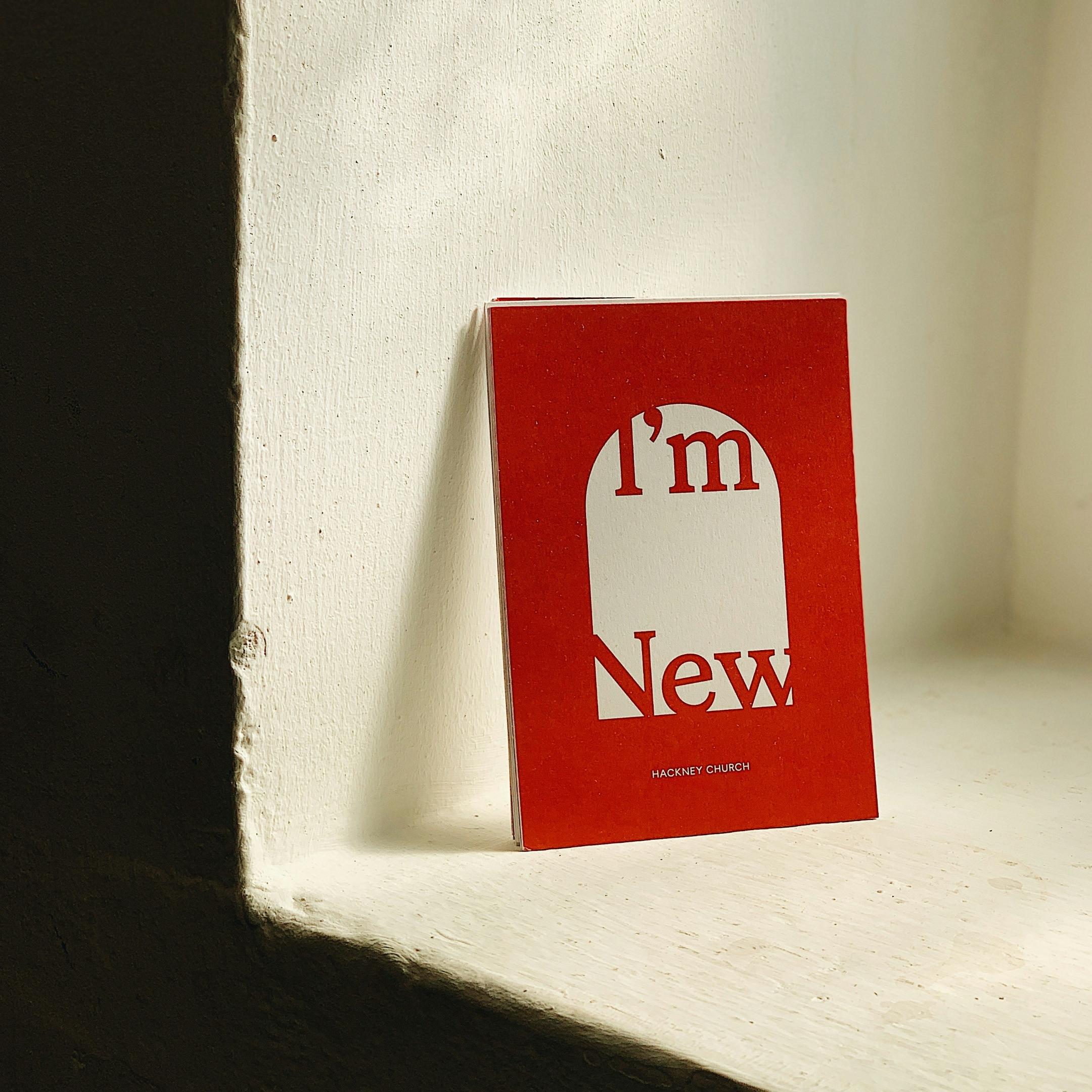Ein rotes Buch lehnt an einem Fenstersims an der Wand. Auf dem Cover steht 'I'm new'