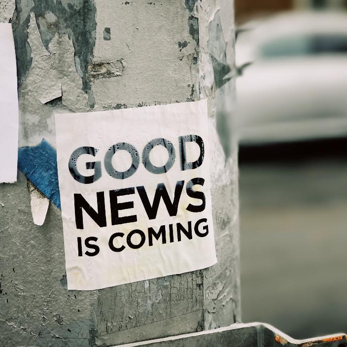 Auf einem Laternenmast ist ein Aufkleber mit der Aufschrift Good News is coming angebracht
